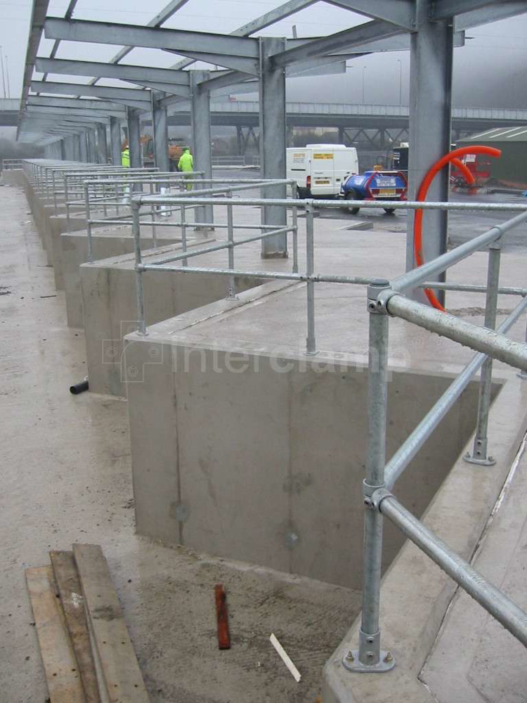 Close-up of Interclamp pipe clamp fittings and tubes forming a sturdy safety guardrail at a recycling centre, providing reliable protection for users.